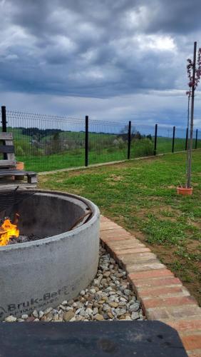 a fire pit in a field with a fence at Dom na Ubocy in Groń