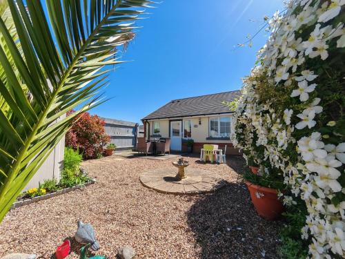 a garden with a house and some white flowers at Fully accessible bungalow by the Beach in Port Talbot