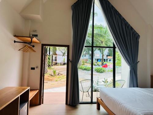 a bedroom with a bed and a large window at Khaosok Sunset Resort in Khao Sok National Park