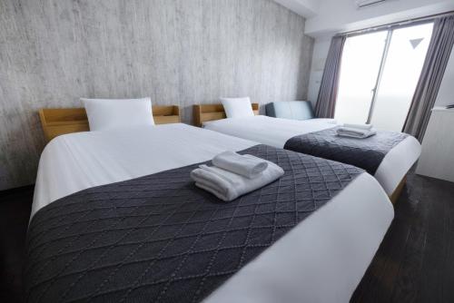 two beds in a hotel room with towels on them at Ue优宜民宿 in Osaka