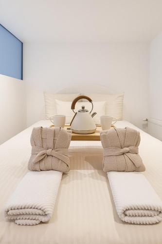 ストラスブールにあるLe Ptit Saint Florent - Studio Indépendant & Spaのタオル2枚とティーケトルが置かれたベッド
