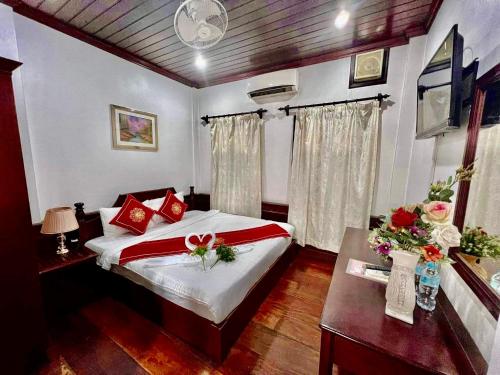 a bedroom with a bed and a table with flowers on it at Villa Phathana Royal View Hotel in Luang Prabang