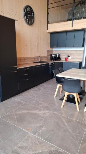 une cuisine avec une table et une horloge au mur dans l'établissement Chalet moderne entre Evasion Design et Nature, à Ruynes-en-Margeride