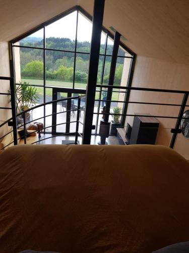 une chambre avec un lit et une grande fenêtre dans l'établissement Chalet moderne entre Evasion Design et Nature, à Ruynes-en-Margeride