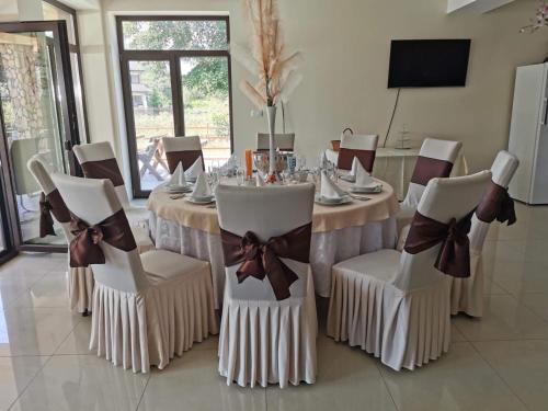 a dining room with a table and chairs with bows at Eden Villa in Ocina de Jos