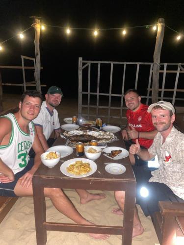 a group of men sitting around a table with food at Beach Escape in Arugam Bay