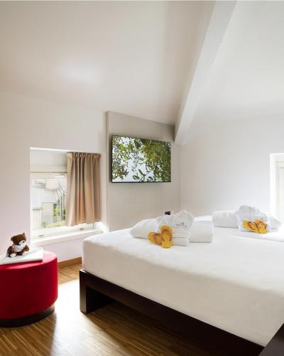a white bedroom with two beds and a red stool at Astoria Resort in Riva del Garda