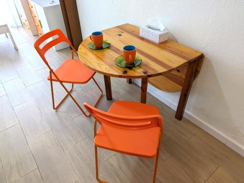 a wooden table with two chairs and two cups on it at IslaOC Apartamentos - Estudio con acceso privado y directo a la Playa in Isla Cristina