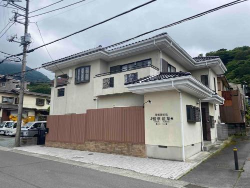 a white house with a red fence on a street at 箱根御泊処-桜華- 049aH in Hakone