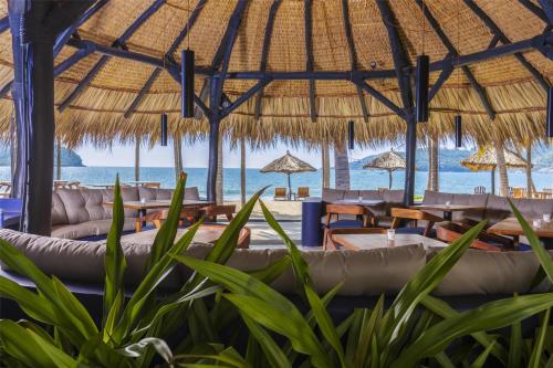 a restaurant with tables and chairs and the beach at Thompson Zihuatanejo, A Beach Resort, by Hyatt in Zihuatanejo