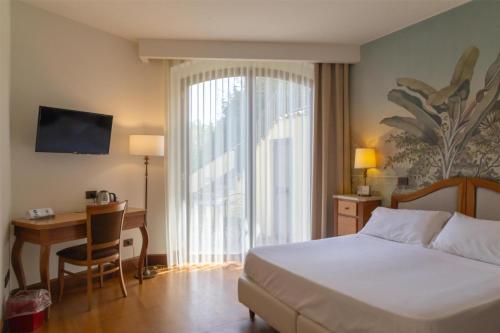 a hotel room with a bed and a desk and a window at Best Western Hotel Santa Caterina in Acireale