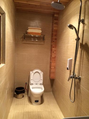 a small bathroom with a toilet and a shower at Tourist Courtyard Hotel in Jianchuan