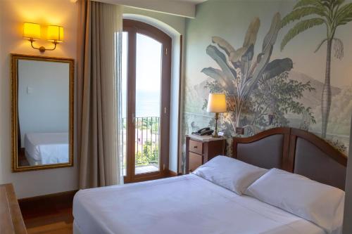 a bedroom with a bed and a mirror and a window at Best Western Hotel Santa Caterina in Acireale