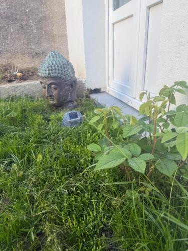 a statue sitting in the grass next to a door at Maisonnette avec Jardin, Piscine, Netflix in Vichy