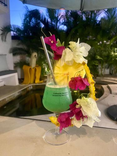 a drink in a glass on a table with flowers at Cosy Guest House Sous le Badamier in Grand Baie