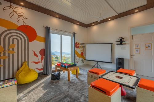 a living room with orange chairs and a screen at The Social Stays Bir formerly ArtBuzz in Bīr