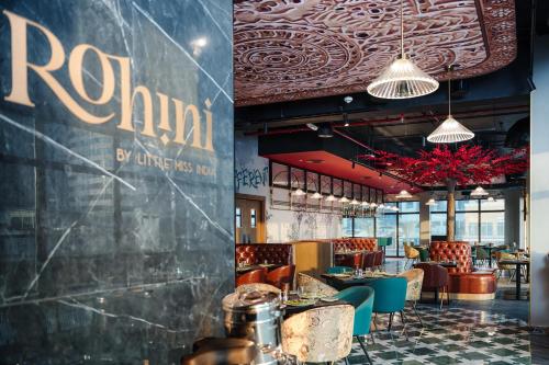 a restaurant with tables and chairs and a wall at Mövenpick Hotel Jumeirah Lakes Towers Dubai in Dubai