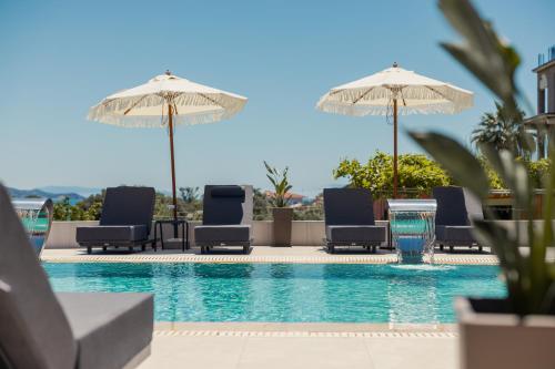 a swimming pool with lounge chairs and umbrellas at Remenata in Lixouri