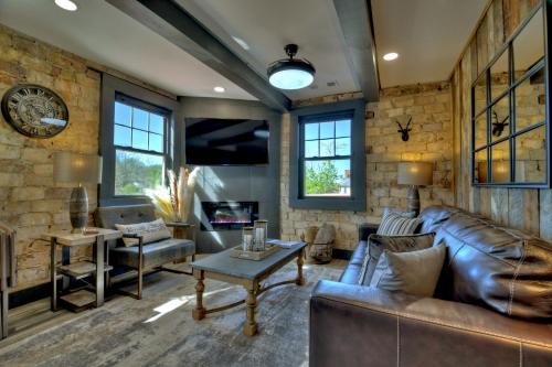 a living room with a leather couch and a stone wall at The Penthouses on Main - Downtown Blue Ridge in Blue Ridge