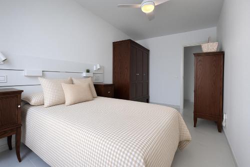 a white bedroom with a bed with a checkered blanket at Apartamento Maresía in Candelaria