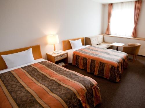 a hotel room with two beds and a window at Sakaide Grand Hotel in Sakaide