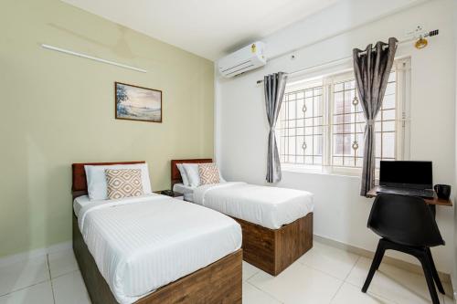 a bedroom with two beds and a desk with a laptop at Wandr Hotel Brookefield, Bangalore in Bengaluru