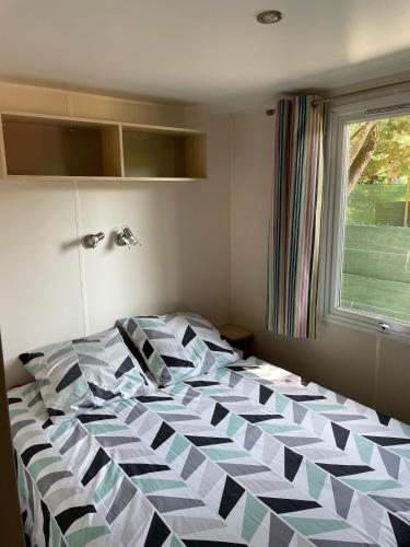 un grand lit dans une chambre avec une fenêtre dans l'établissement Mobil home dans camping 4 étoiles au calme, à Saint-Hilaire-de-Riez