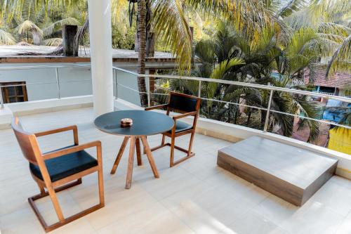 a balcony with a table and chairs and palm trees at Casa Aqua Mandrem in Mandrem