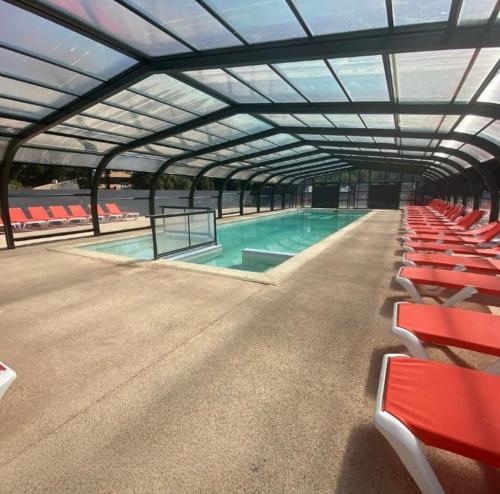 una grande piscina con sedie rosse e una struttura sopraelevata di Mobil home dans camping 4 étoiles au calme a Saint-Hilaire-de-Riez