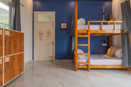 a bedroom with two bunk beds and a blue wall at The Social Stays Bir formerly ArtBuzz in Bīr