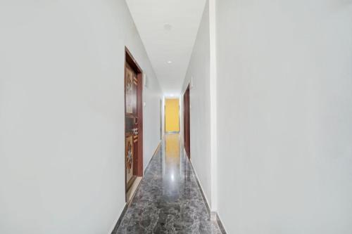 a hallway with white walls and a marble floor at Hotel O Friends Inn in Patna