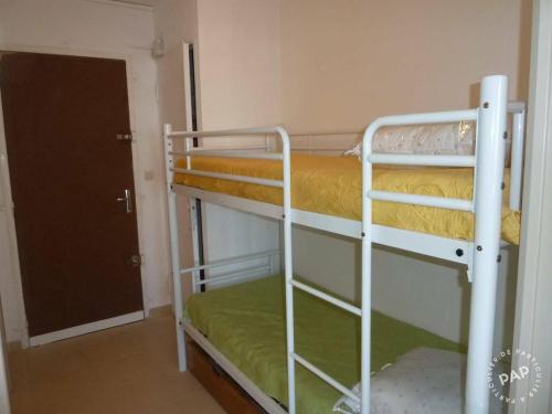- deux lits superposés dans une chambre avec une porte dans l'établissement Studio Cabine Climatisé tout près de la plage, au Grau-du-Roi