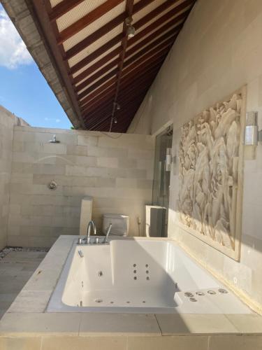 eine Badewanne in einem Badezimmer mit einem Gemälde an der Wand in der Unterkunft Enchanting Canggu Villa in Tumbak Bayuh
