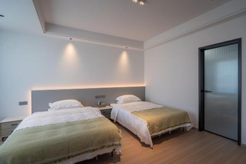 two beds in a bedroom with white walls and wood floors at Daishan Mountain and Sea Cloud Homestay Sunrise Seaview Bed and Breakfast in Zhoushan