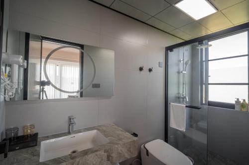a bathroom with a sink and a toilet and a mirror at Daishan Mountain and Sea Cloud Homestay Sunrise Seaview Bed and Breakfast in Zhoushan