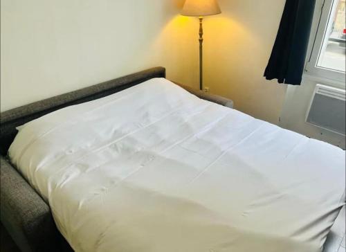 un lit blanc dans une chambre avec une fenêtre dans l'établissement Coquebert studio confortable proche centre ville, à Reims