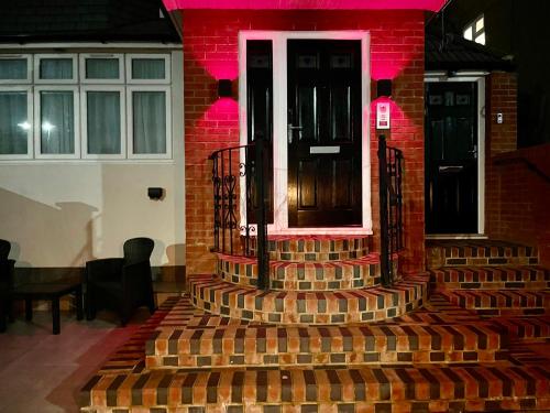 einem roten Backsteingebäude mit einer Tür und einer Treppe in der Unterkunft Luxe Villa, 5 En-suite Bedrooms - West London - Wembley Stadium 5KM away in Harrow on the Hill