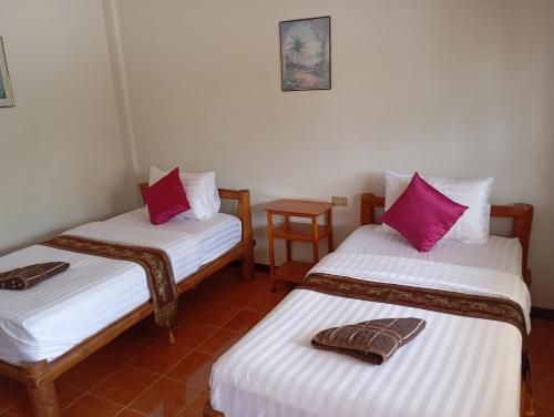 two beds in a room with pink pillows on them at MG Guesthouse in Sukhothai