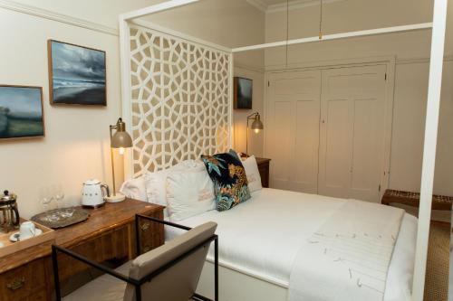 a bedroom with a white bed and a desk at Sonnekus Boutique Hotel & Bistro in Kalk Bay