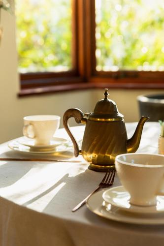 a tea kettle and two cups on a table at Sonnekus Boutique Hotel & Bistro in Kalk Bay