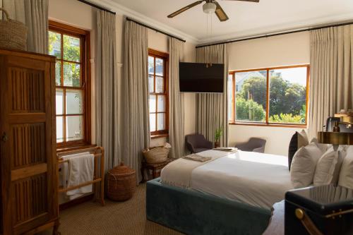 a hotel room with a large bed and windows at Sonnekus Boutique Hotel & Bistro in Kalk Bay