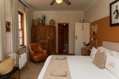 a bedroom with a white bed and a chair at Sonnekus Boutique Hotel & Bistro in Kalk Bay