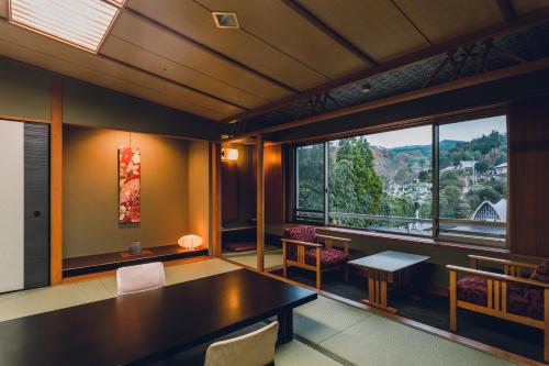 a room with a table and chairs and a large window at Tamatsukuri Grand Hotel Choseikaku in Matsue