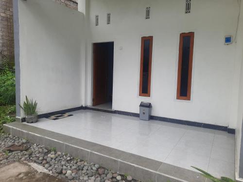 a white house with a door and a stairway at Ayunda Stay & Hostel in Airsatang