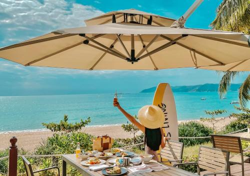 a woman sitting at a table under an umbrella at the beach at MGM Grand Sanya in Sanya