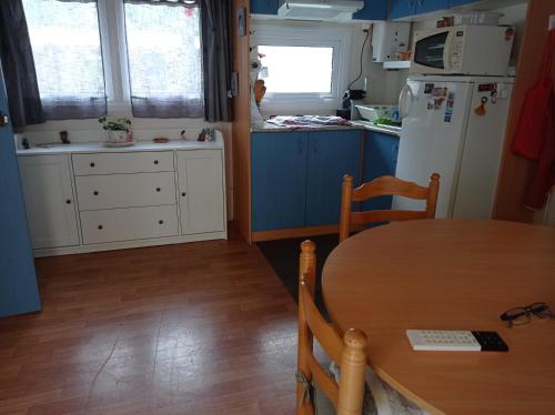 Il comprend une cuisine équipée d'une table et d'un réfrigérateur. dans l'établissement Mobil-home, à Capbreton