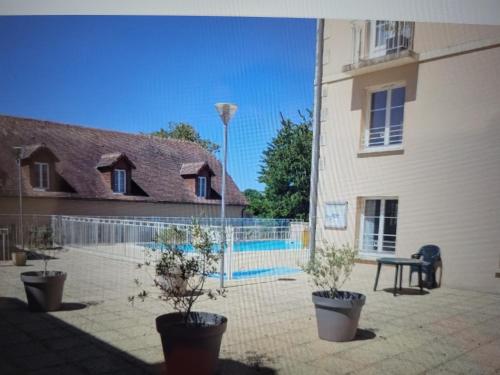 une cour avec des plantes en pot à côté d'un bâtiment dans l'établissement Studio avec piscine, à La Roche-Posay