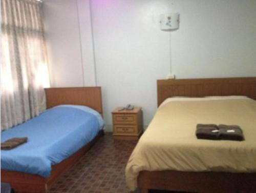 a bedroom with two beds and a dresser at White Orchid Inn I in Bangkok