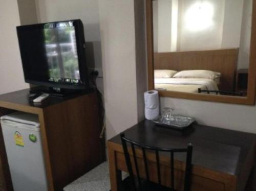 a room with a tv and a table with a mirror at White Orchid Inn I in Bangkok
