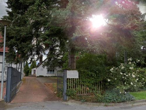 a tree in front of a house with a fence at Pension Werre Stern in Bad Oeynhausen